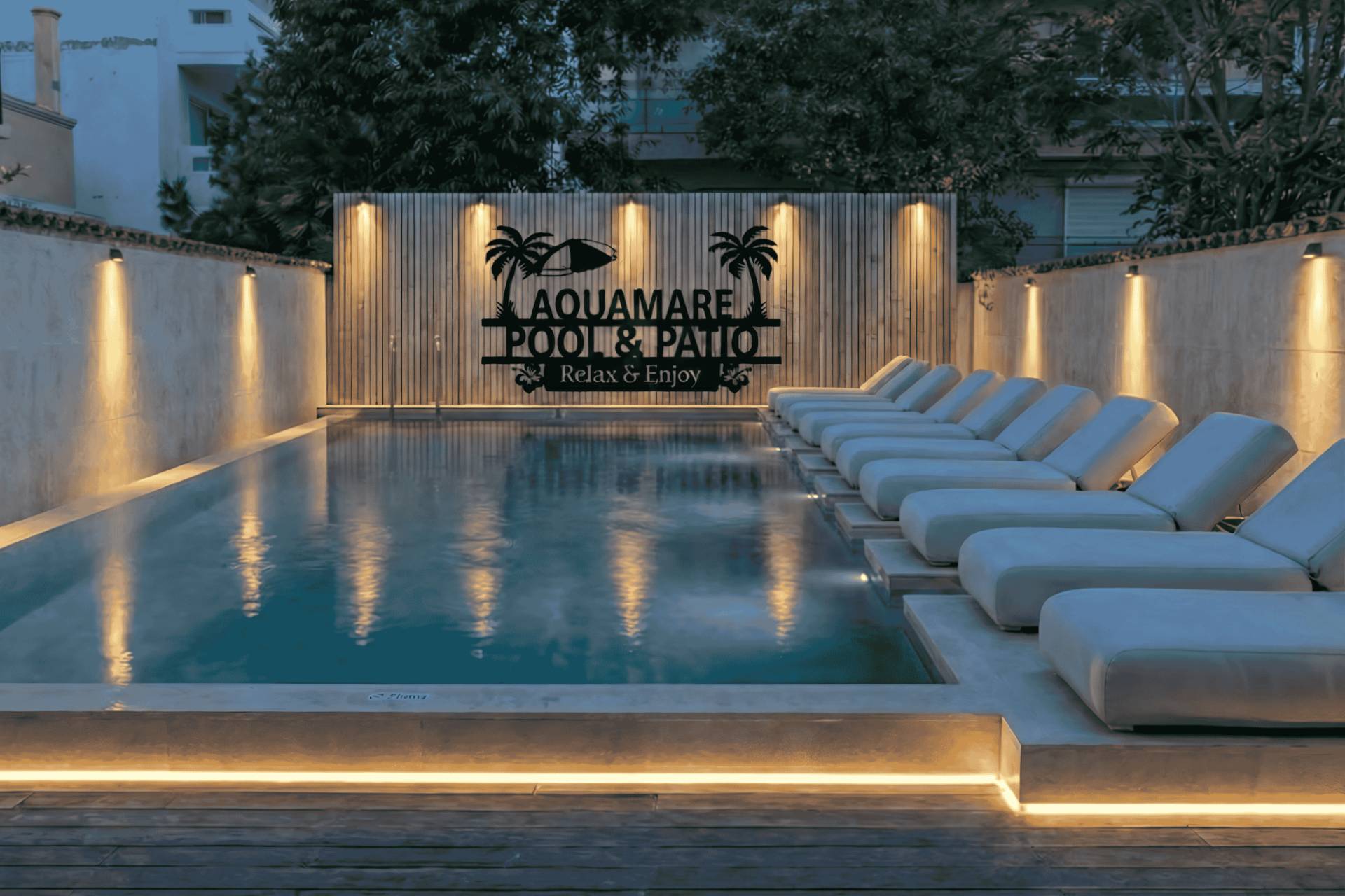 
Το Aquamare Pool & Patio το σούρουπο, με φωτισμένη πισίνα γλυκού νερού και αναπαυτικές ξαπλώστρες