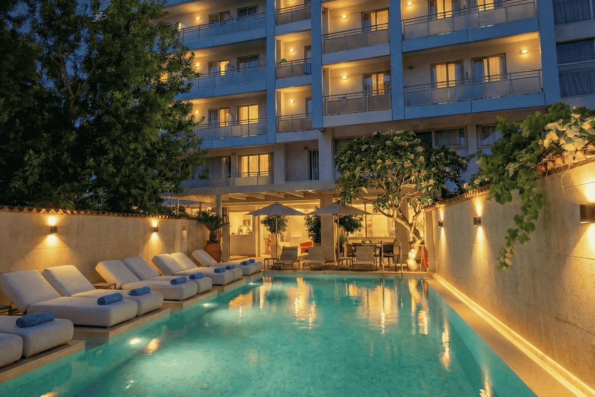 
Το Aquamare City & Beach Hotel το σούρουπο, με φωτισμένη εξωτερική πισίνα και αναπαυτικές ξαπλώστρες