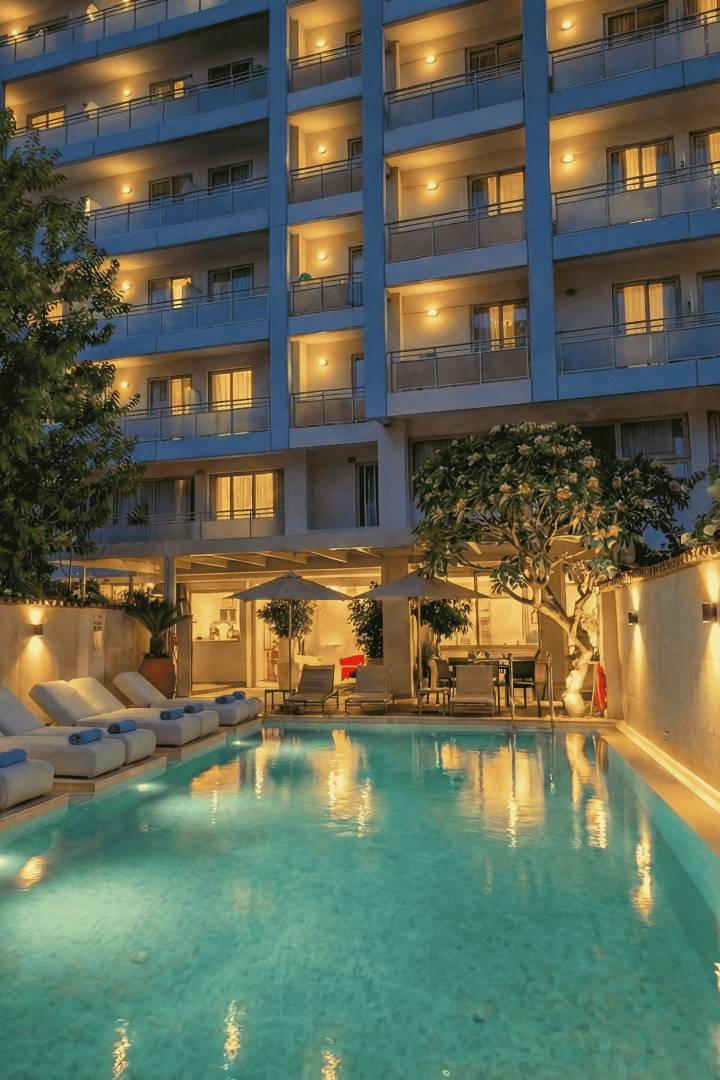 
Aquamare City & Beach Hotel at dusk with illuminated balconies, outdoor pool and poolside loungers